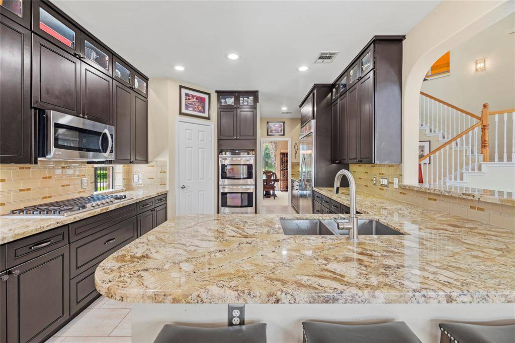 Functional kitchen featuring an L-shaped countertop with dual sink, built-in stovetop and double oven, microwave, and plenty of cabinets for storage. A convenient door leads directly to the pantry for easy access.