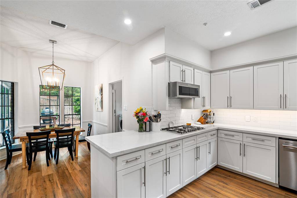 The chef’s kitchen, outfitted with high-end appliances, overlooks the open dining area and offers picturesque views of the beautifully landscaped backyard.