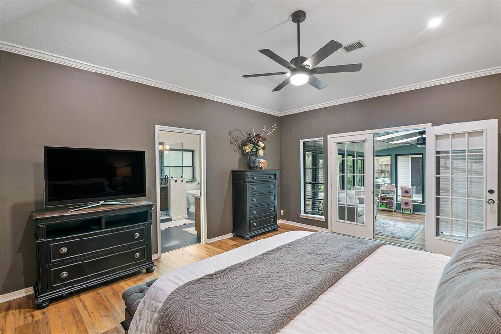 The primary bedroom features glass doors that lead directly into the sunroom, creating a seamless connection to the tranquil outdoor space.