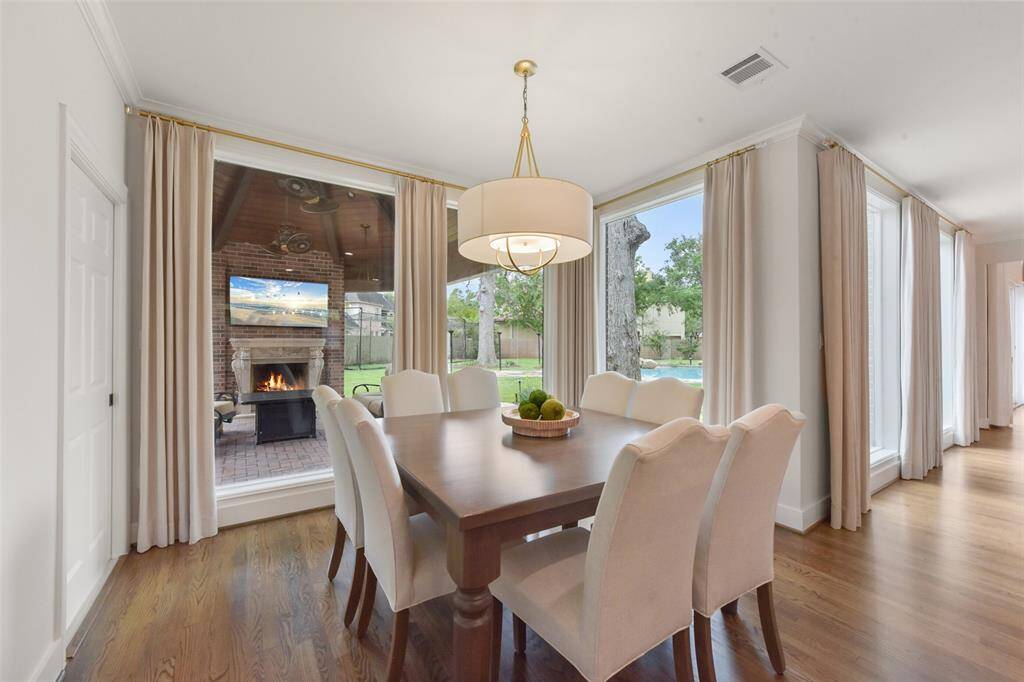 Breakfast room with custom drapes, wood floors and elegant light fixture overlooks the loggia and pool. Excellent set up for family dinners or your first cup of coffee in the morning.