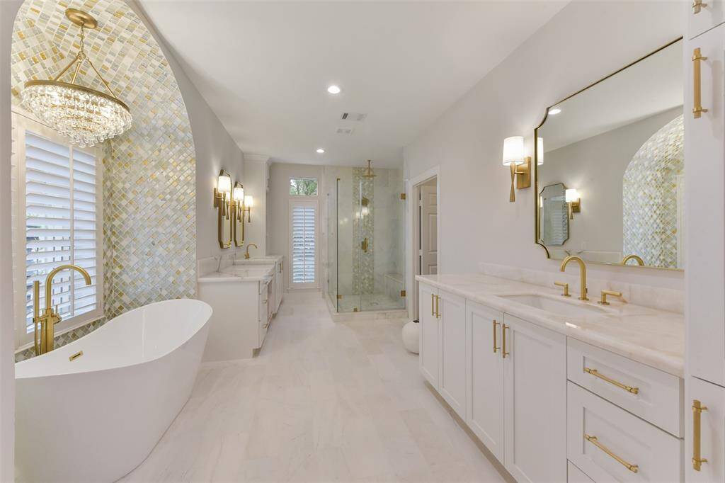 Award winning primary bathroom remodeled in 2023, features elegant marble flooring, his and hers separate sinks and vanities, fjord quartzite, luxurious stand-alone bathtub with a statement chandelier, a coordinating chandelier in closet and designer-selected high-end decorative tile throughout.