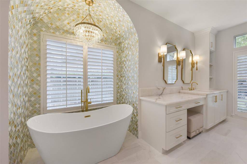 Soak away your worries in the bathtub niche, surrounded by elegant tile, brass fixtures and sparkling chandelier.