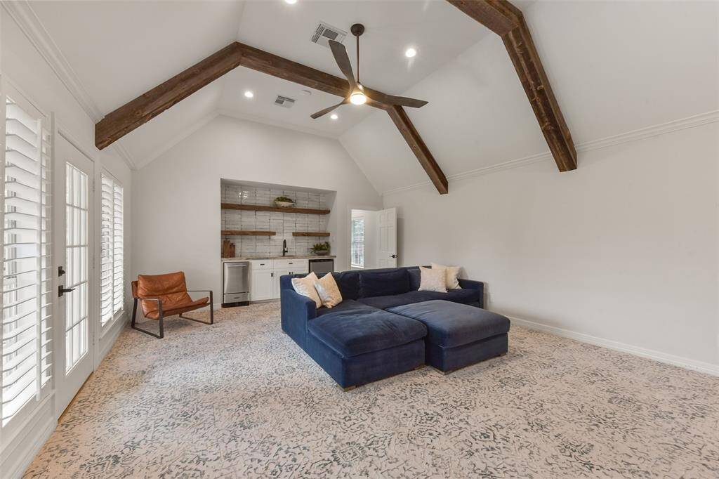 Media room features high ceilings, reclaimed wood beams, upgraded ceiling fan, plush designer carpet, wet bar, designer tile, ice maker and mini refrigerator make this media room top notch.