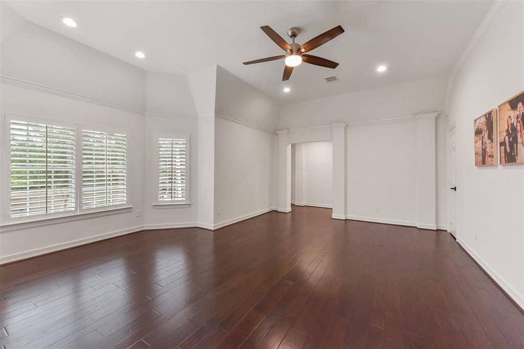 Upstairs living or game room features wood floors, plantation shutters, updated lighting, and panoramic views of the backyard.