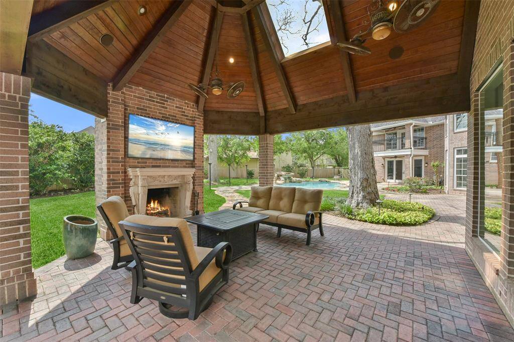 Brick-paved loggia features vaulted, wood-planked ceiling, fireplace, and outdoor entertaining area.