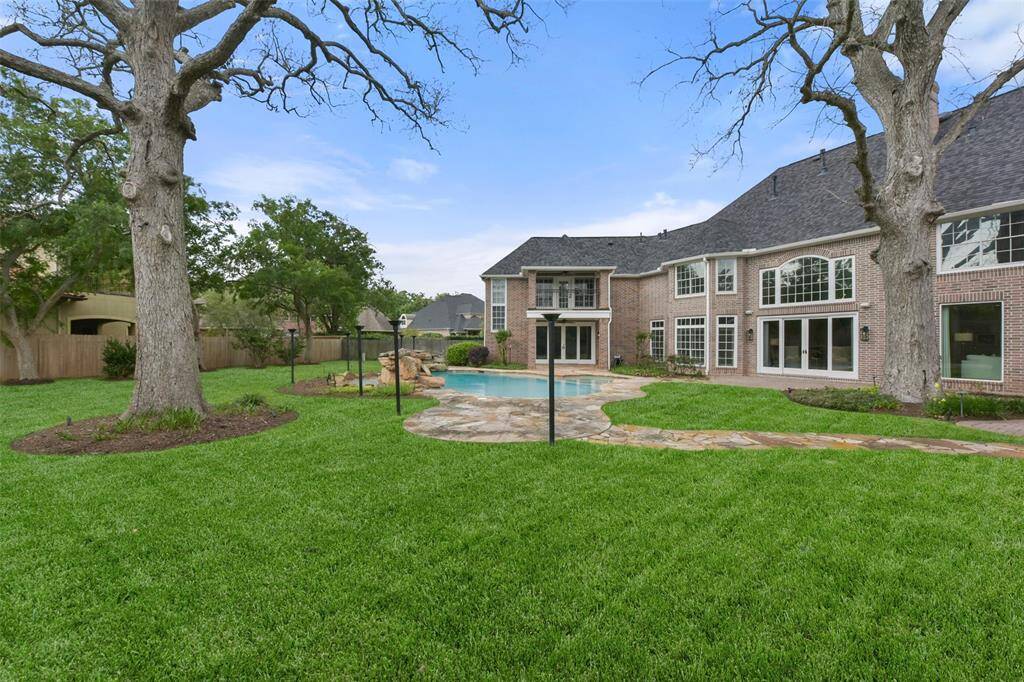 Plenty of grassy area overlooks the pool and large trees.