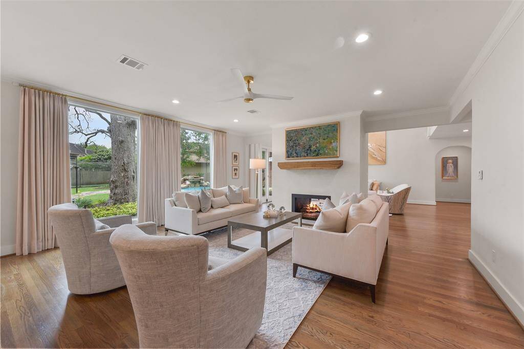 The opposite side of the dual-sided fireplace features a reclaimed wood mantel, open floor plan, custom drapery.  and serves as a focal point in the family room.
