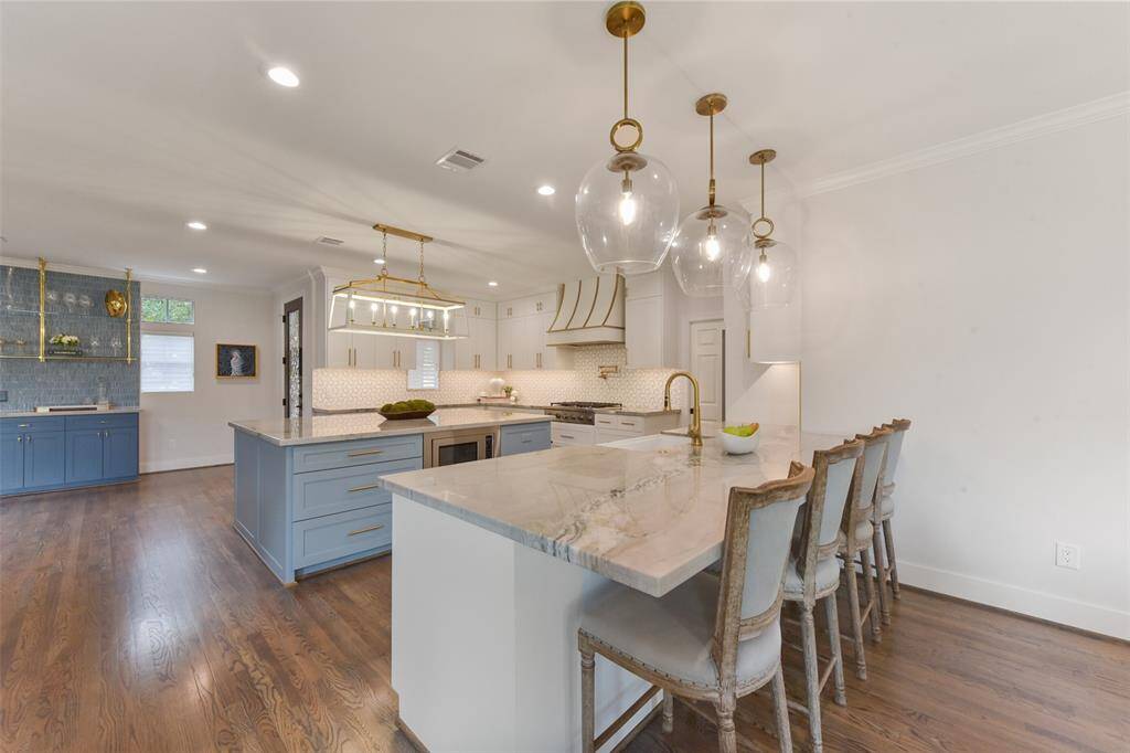 Exquisite quartzite countertops, bespoke custom cabinetry, a designer vent hood, and a sophisticated high-end tile backsplash. Dual islands provide both functionality and style, ideal for entertaining and everyday living.
