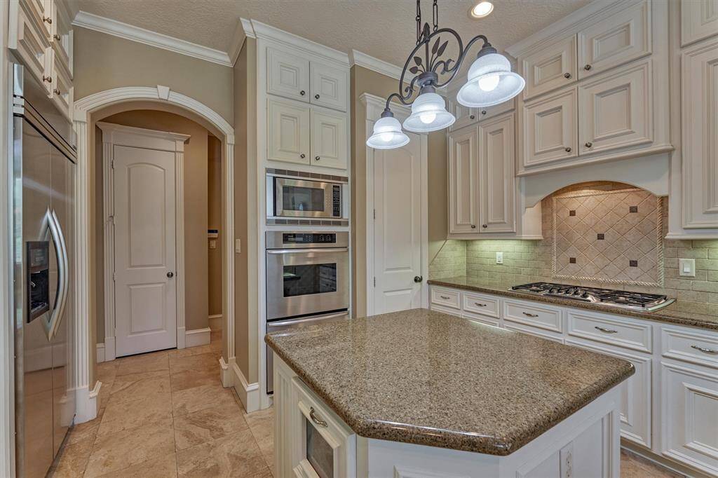Counter-to-ceiling cabinets for optimal storage, including a matching wood hood for perfect symmetry. Note the arched, wood-trimmed opening to a back hallway that ideally serves as a pass-through to the dining room and tucked away mud/utility room.