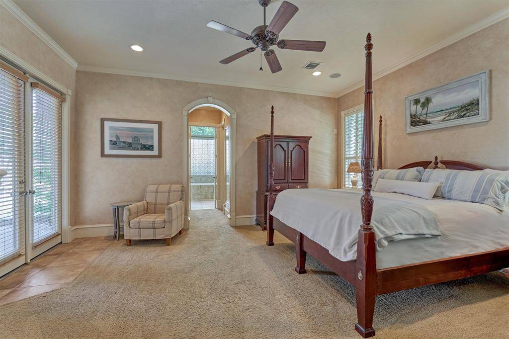 The secluded owner's retreat is wrapped in Venetian plaster, molding, and features sitting area with a private exterior door to the covered back patio.