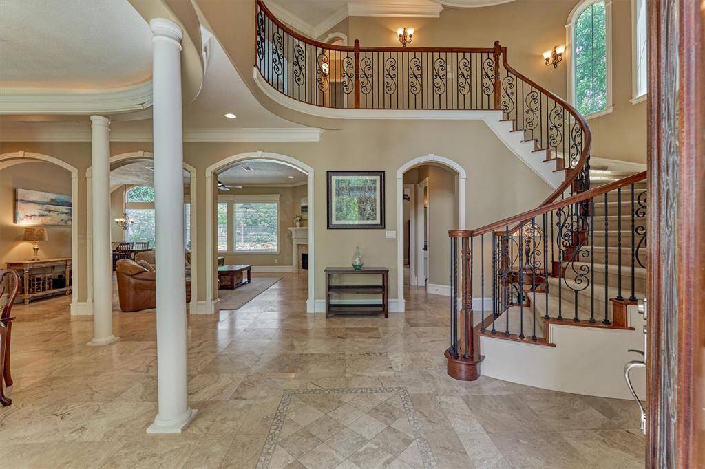 Step inside the grand 2-story foyer entry boasting a stunning curved stairway, continuous tile flooring throughout, and soaring ceilings.