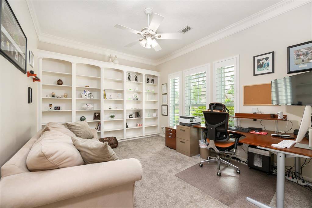 This bright and spacious home office is designed for functionality, featuring custom built-in shelves and an abundance of natural light streaming through multiple windows. The room’s thoughtful layout and architectural details create an inviting space for work or relaxation.