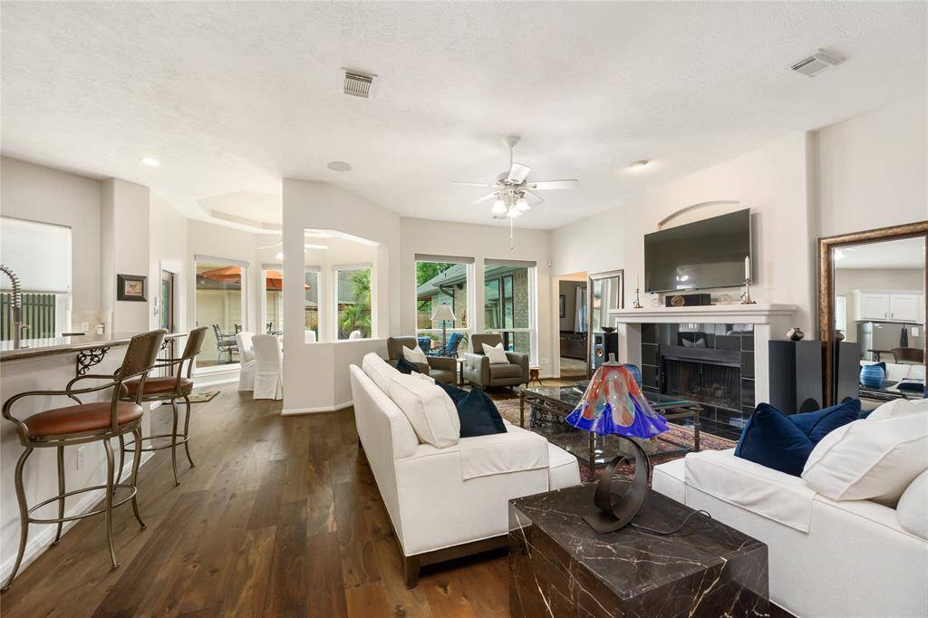 The spacious living area boasts beautiful hardwood floors and a cozy fireplace, all bathed in natural light from large windows. The open layout seamlessly connects to the dining area and kitchen, complete with a breakfast bar—perfect for entertaining and everyday living.