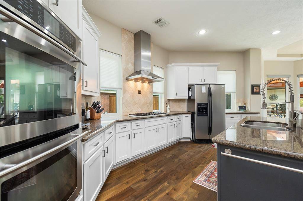The spacious island serves as a functional centerpiece, ideal for meal prep or casual gatherings. Large windows fill the space with natural light, while the elegant hardwood floors enhance the open, airy atmosphere.