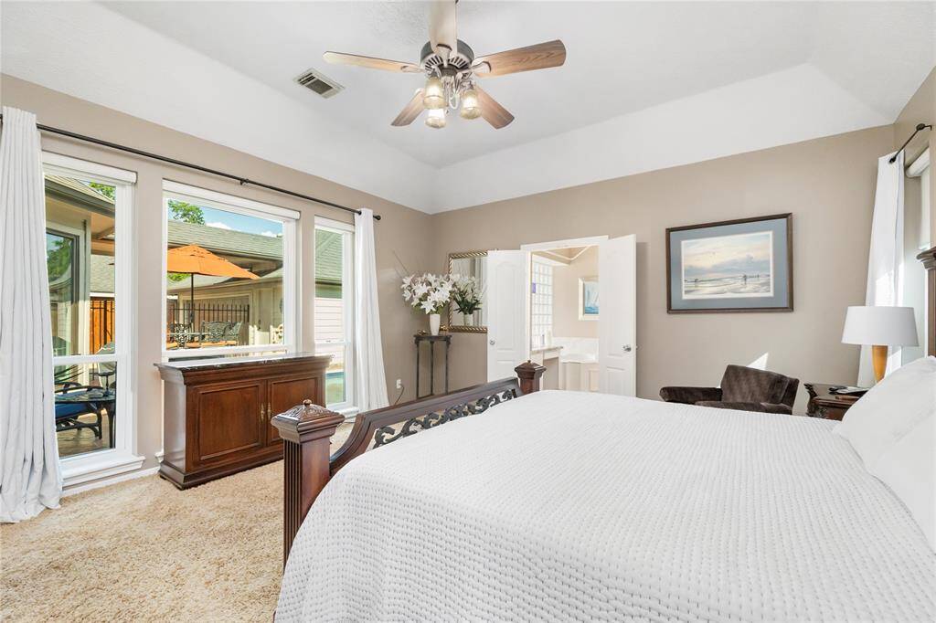 This bright and airy primary suite offers serene views of the sparkling backyard pool through large windows that fill the room with natural light.