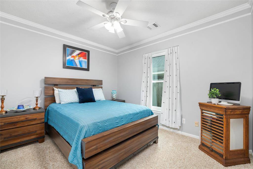 This light-filled secondary bedroom offers a bright, airy feel with soft carpeting, neutral tones, and generous natural light. The spacious layout makes it ideal for accommodating family, guests, or creating a versatile space tailored to your needs.