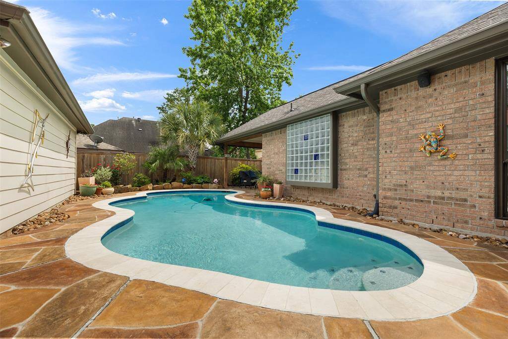 The beautiful in-ground pool, re-done in 2019, is surrounded by a stone patio, creating a tranquil retreat. A brick wall and wooden fence provide seclusion, while lush plants and thoughtful landscaping add a touch of serenity, making this outdoor space both inviting and peaceful.