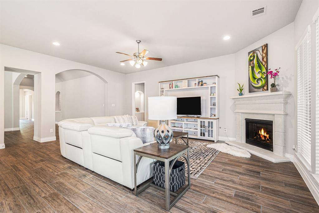 Spacious living room features elegant wood-look tile flooring, a cozy fireplace, and ample natural light.