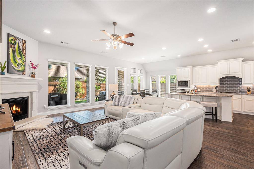 The spacious open-concept living area features large windows and a modern kitchen with white cabinetry and a breakfast bar. Perfect for entertaining and family gatherings.