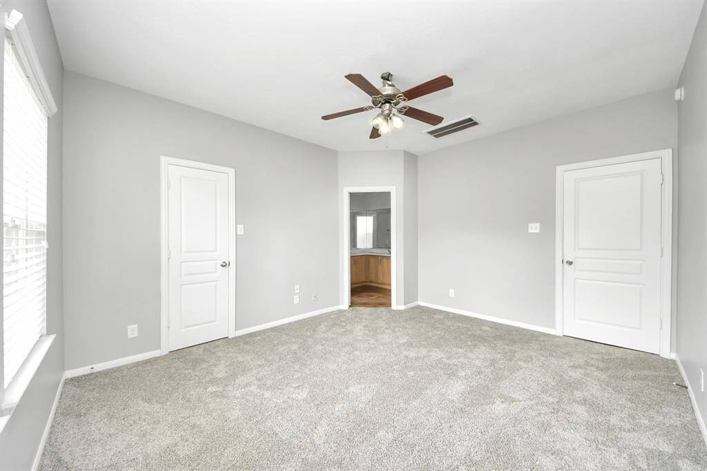 Serene primary bedroom featuring soft carpeting, ample natural light, and a stylish ceiling fan.