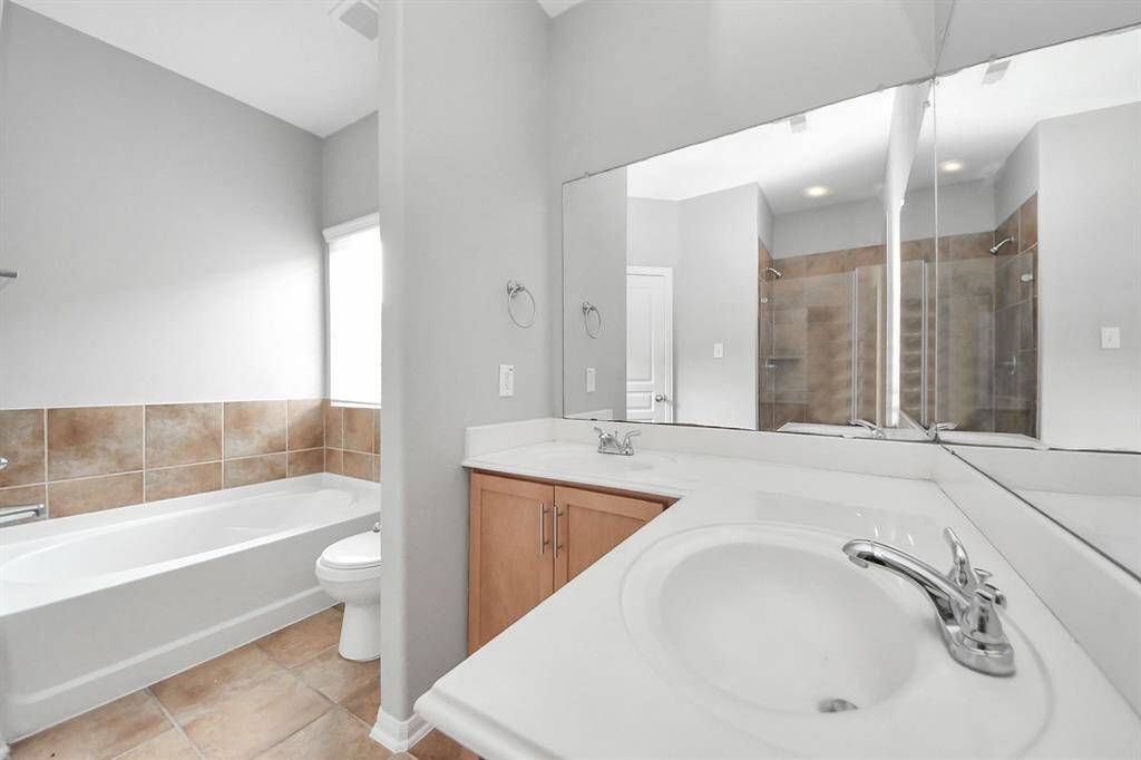 Luxurious primary ensuite featuring a spacious layout with a relaxing bathtub, sleek shower, and elegant vanity. Perfect for unwinding in style.