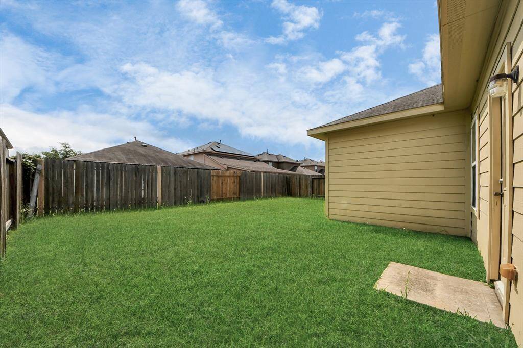 Spacious backyard with lush green grass, enclosed by a wooden fence, ideal for outdoor activities.