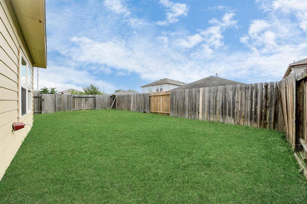 Spacious backyard with well-maintained grass, bordered by a wooden fence, offering privacy and a great area for outdoor activities.