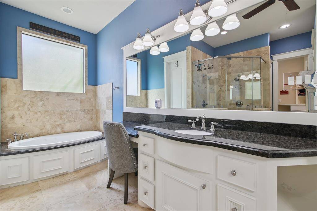 It features a large, separate shower and dual vanities, providing ample space for daily routines.