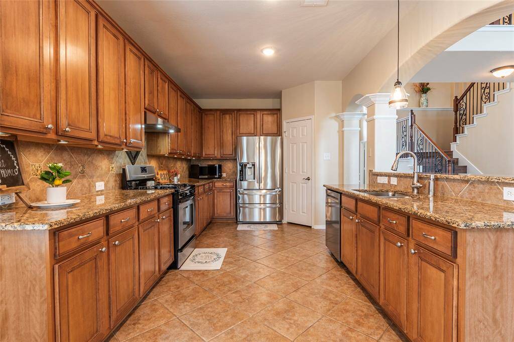 Kitchen area with tile flooring, beautiful wood cabinets, granite counter tops, tile backsplash and stainless steel appliances, refrigerator included.
