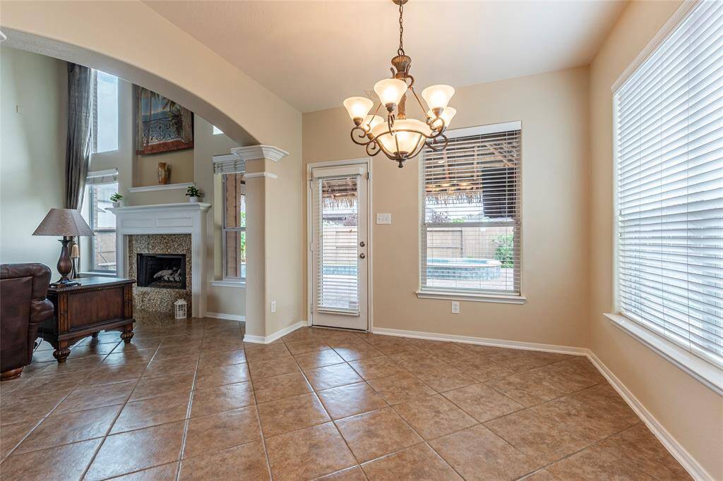 Spacious breakfast area with tile flooring and pool and backyard views.