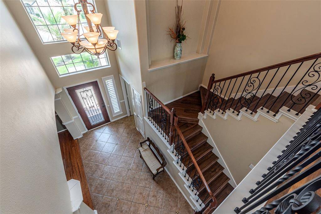 Beautiful wood staircase with wrought iron railing leads  to the 2nd level from the entryway.