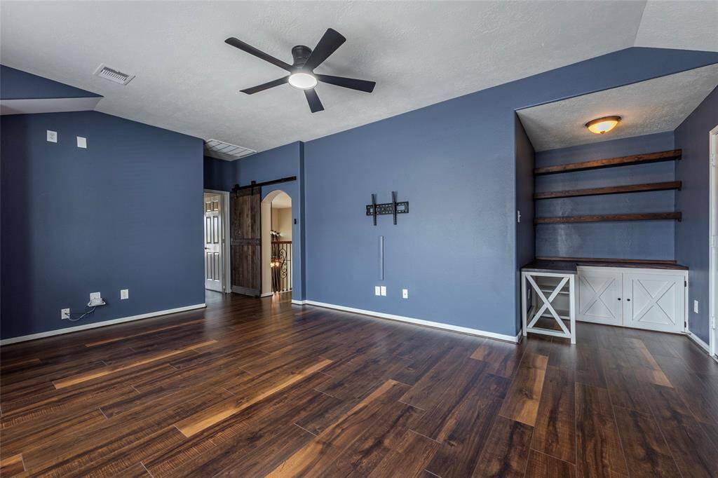 Large gameroom with built-in desk and shelving. To the right is a HUGE walk-in attic, decked for storage space.