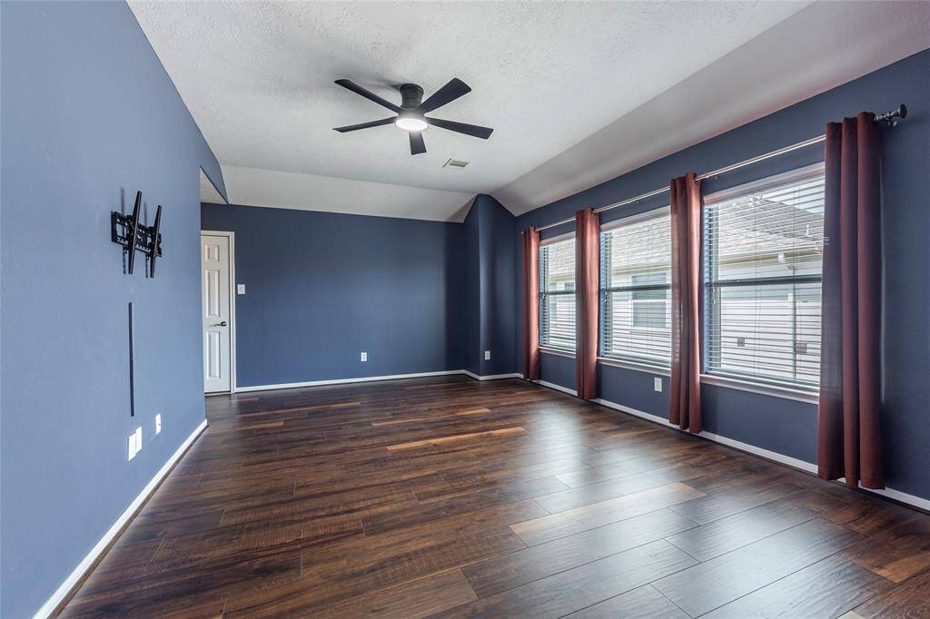 Spacious upstairs game room with wood flooring, custom drapes and 2" blinds.