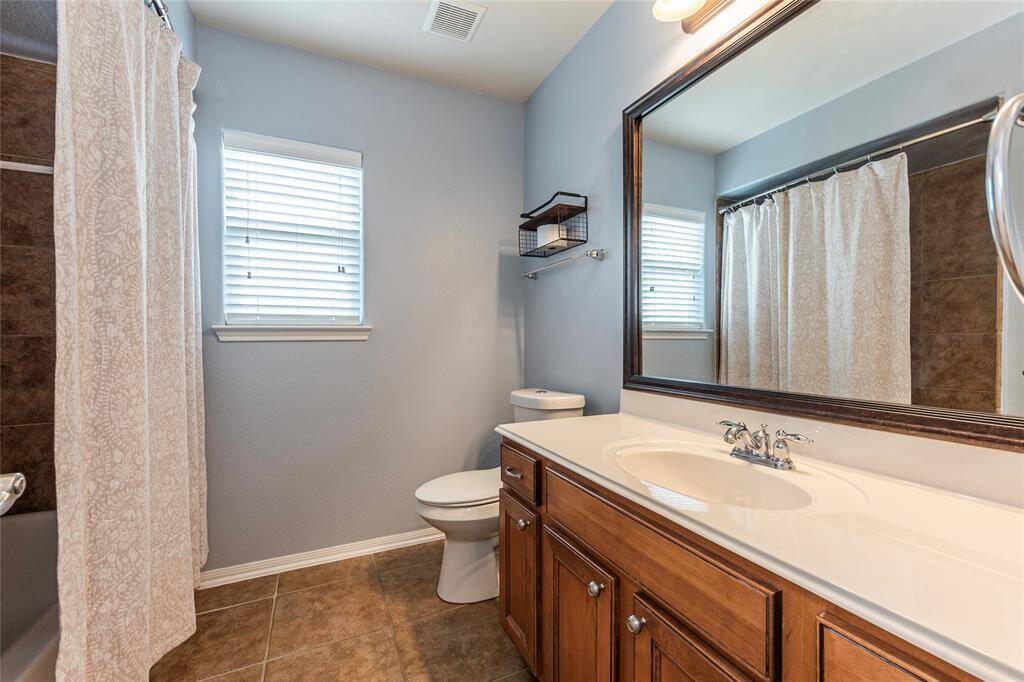 Large upstairs full bathroom with framed vanity mirror, tile flooring and shower/tub combo.