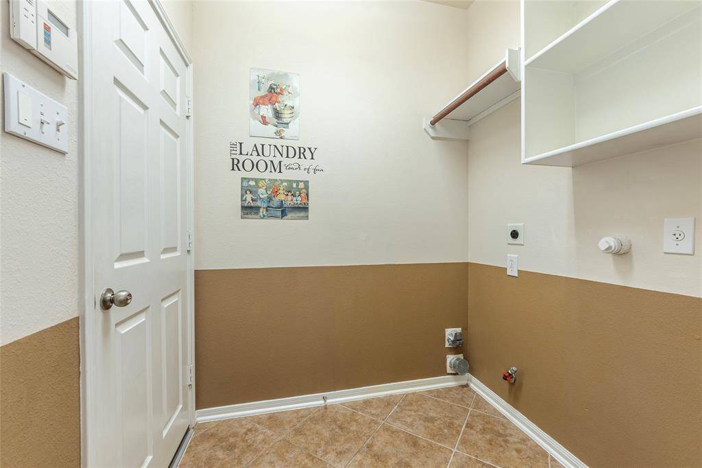 Utility room on the 1st floor with storage shelves, gas connection and tile flooring.