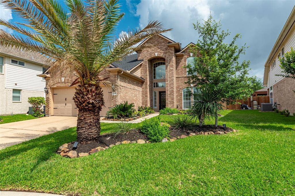 Tropical landscaping accents the front exterior of the home.