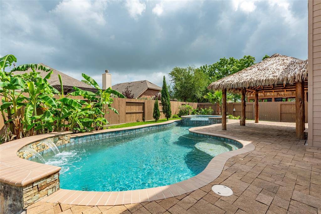 Private backyard with only 1-story homes around. Large sparkling swimming pool with water fall feature and tropical landscaping gives the home a resort style feel.
