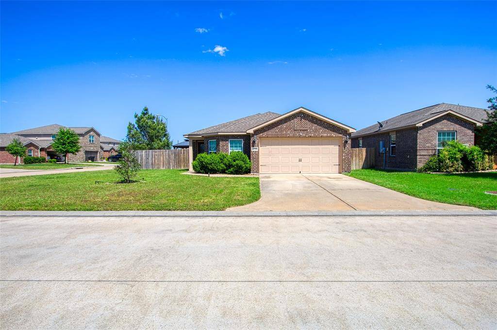 A charming single-story brick home with a two-car garage, surrounded by a neatly maintained lawn and located in a quiet neighborhood.