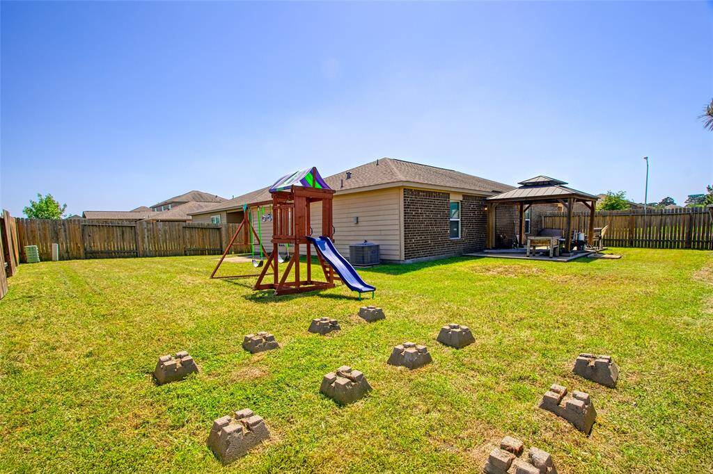 A spacious back yard is enclosed by a wooden fence, providing privacy and a safe space for all activities.
