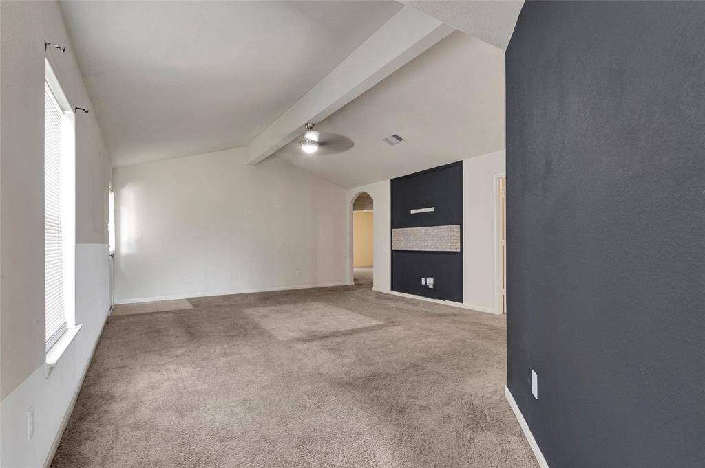 Spacious living room with vaulted ceiling. Large windows provide natural light. Ideal for a comfortable and inviting living space.