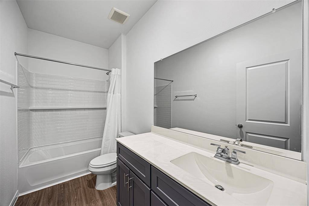 The secondary bathroom includes a shower and tub combo also with a wide mirror above the sink.