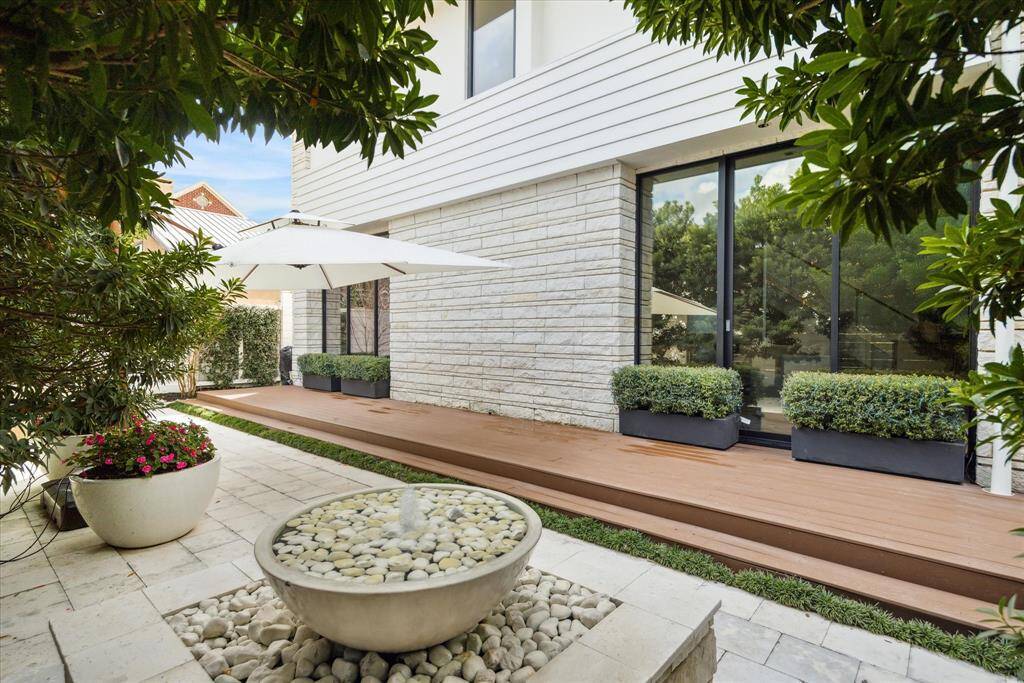Front patio - Professionally landscaped with fountain and Japanese Blueberry trees. 7' privacy cedar fence.. Exterior house lighting. Rainbird sprinkler system. White tile decking. Wired for outdoor speakers. Sliding access gate for convenient maintenance.