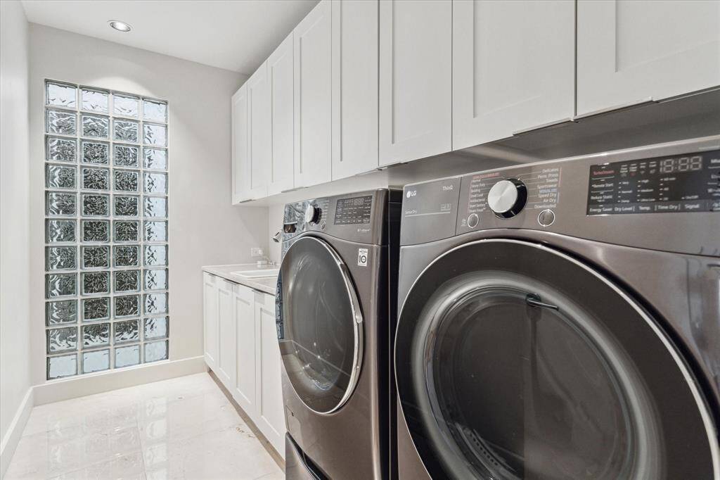 Utility room is located on the second floor. Lots of storage cabinets and counter space and sink. Carrera marble flooring.