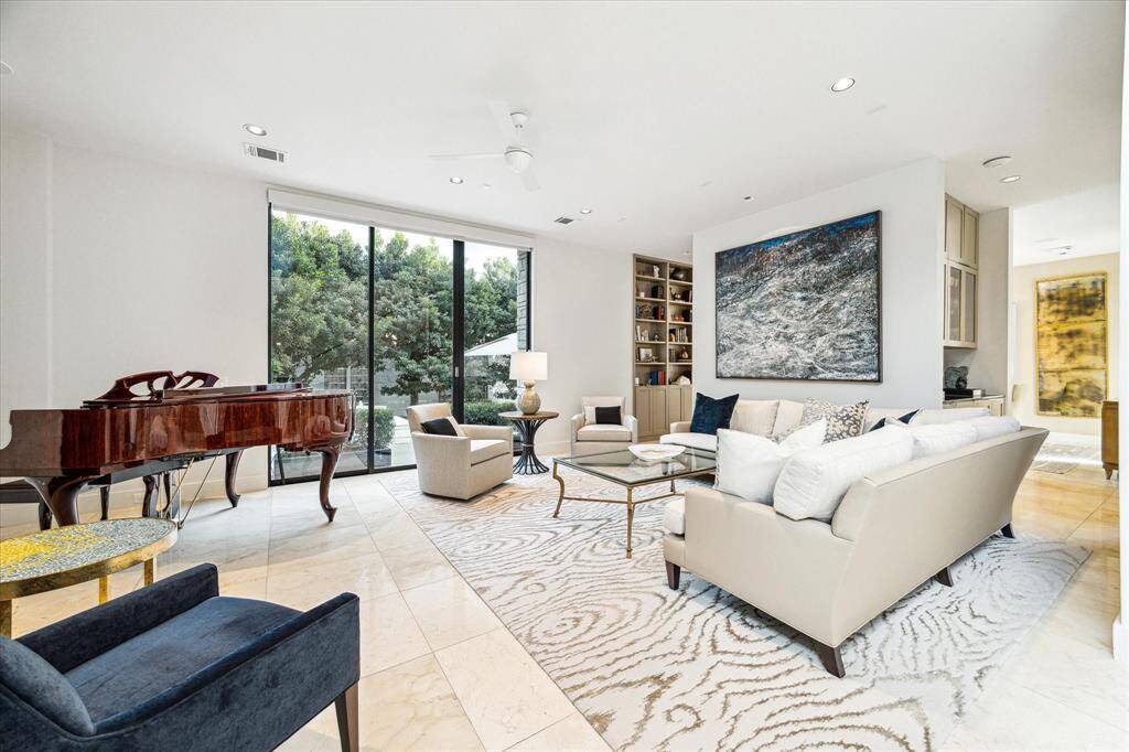 Formal living room features high ceiling, fireplace, plenty of room for a piano and access to the front patio . Carrera marble flooring. Remote Controlled Shades on first floor.