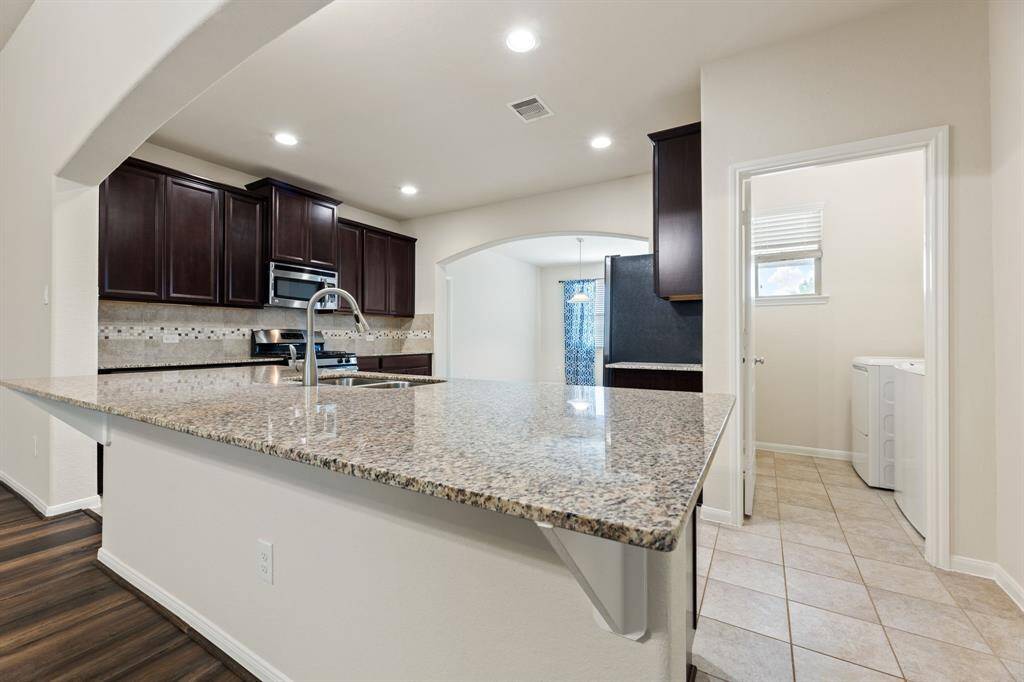Kitchen features a large island, gas oven, and ample pantry space.