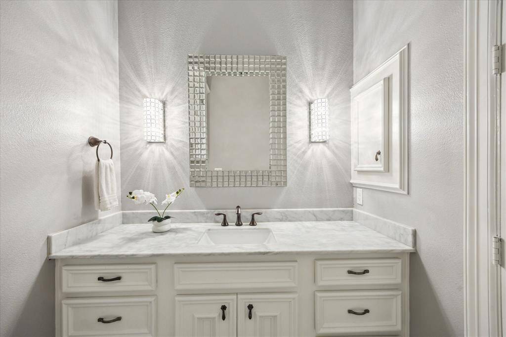 The primary bedroom is an elegant retreat, featuring a custom-built entertainment center, an arched entryway, and hardwood floors. Large windows allow natural light to fill the space, enhancing its sophisticated ambiance.