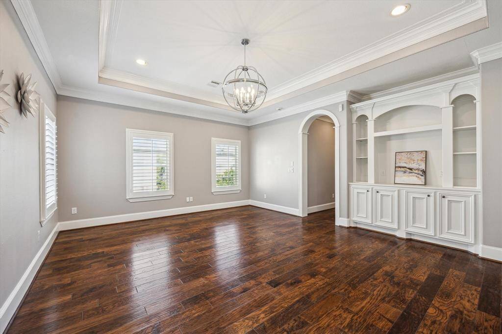 The primary bath is a spa-like retreat, featuring elegant tile floors, a large jetted tub, and a frameless glass shower with dual showerheads and a bench for added comfort. Custom built-ins provide convenient linen and towel storage.