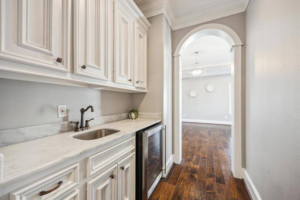 The oversized primary closet features a dual French door entry, multiple custom-built cabinets and shelves designed for shoes and purses, and a spacious wall mirror that enhances the room’s elegant appeal.