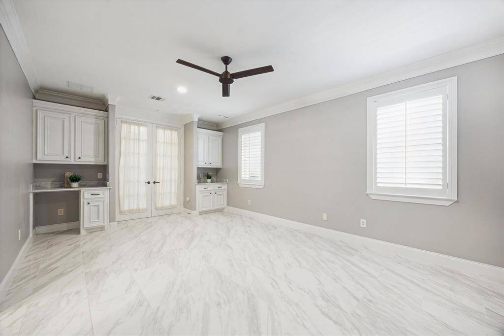 The ensuite bath features elegant marble countertops, a decorative light fixture and mirror, and a spacious shower with a bench, complemented by decorative tile.