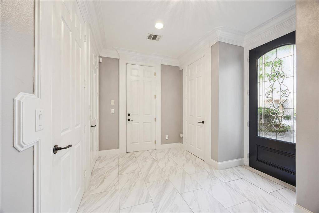 The formal entry showcases soaring 9-foot ceilings, elegant tile flooring, and direct access to the garage. It also includes four spacious storage closets.